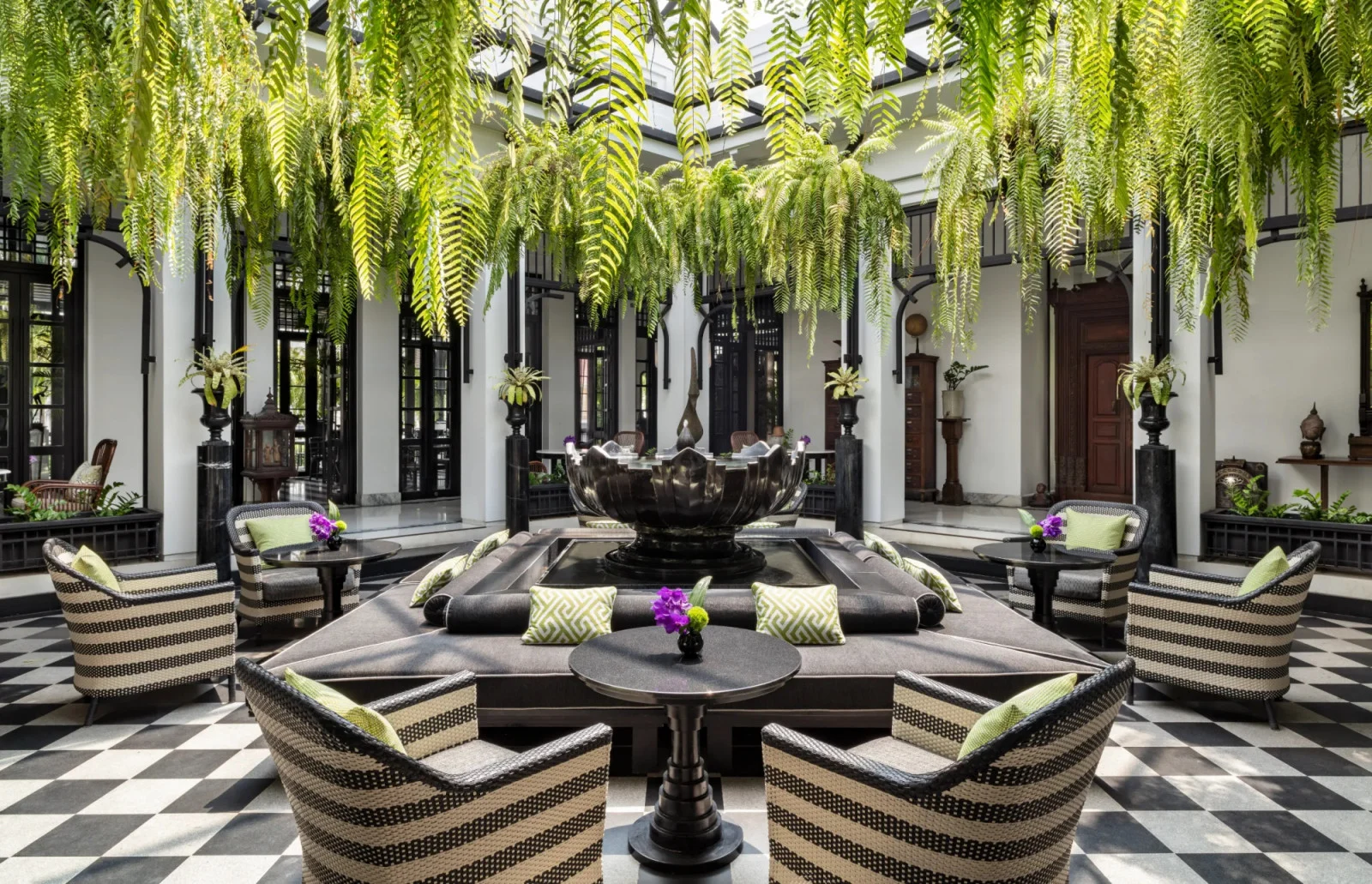 Black and white colonnaded courtyard with tall planting beside a river building