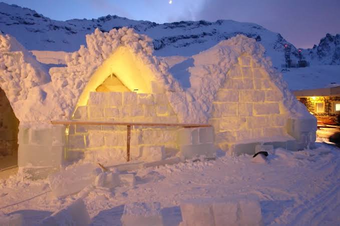 Blocks cut from a frozen lake stacked into a curved wall under a dark sky
